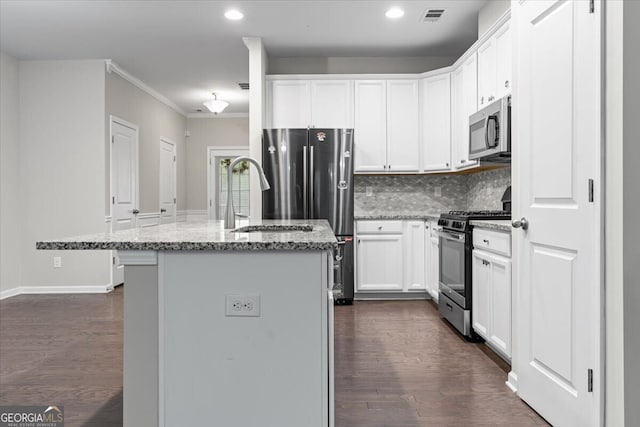 kitchen featuring dark wood-style flooring, appliances with stainless steel finishes, light stone counters, visible vents, and a center island with sink