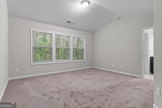 spare room with carpet floors, baseboards, lofted ceiling, and visible vents