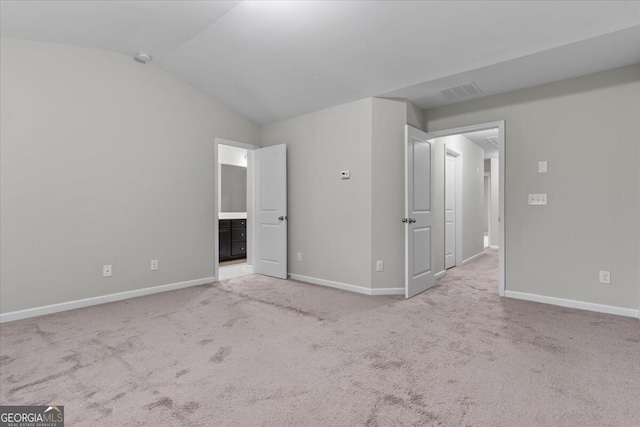 unfurnished bedroom with visible vents, baseboards, light colored carpet, and lofted ceiling