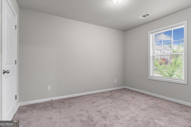carpeted spare room featuring baseboards and visible vents