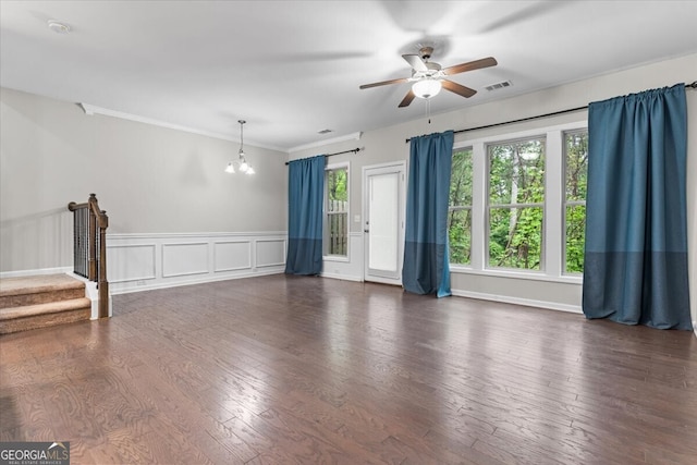 unfurnished living room featuring ceiling fan with notable chandelier, wood finished floors, a wealth of natural light, and a wainscoted wall