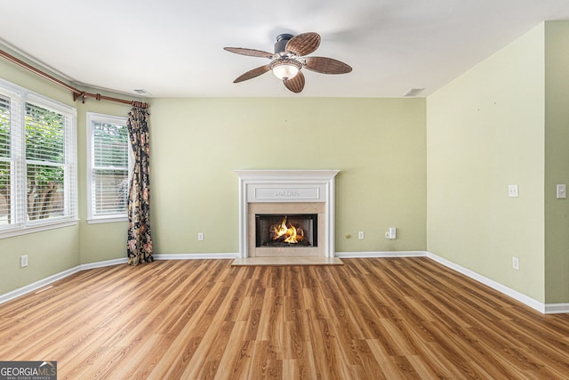 unfurnished living room featuring ceiling fan, baseboards, a fireplace with flush hearth, wood finished floors, and visible vents