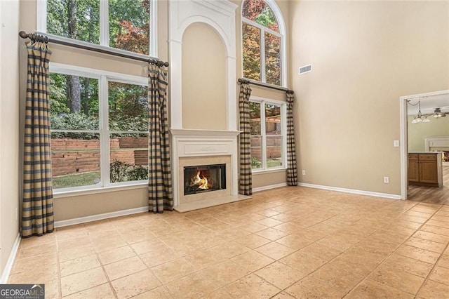 1235 Legend Run, Alpharetta, GA 30005 - unfurnished living room with a towering ceiling, a warm lit fireplace, and plenty of natural light