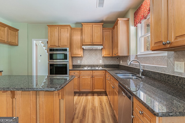 kitchen featuring visible vents, stainless steel appliances, a sink, under cabinet range hood, and light wood-style flooring