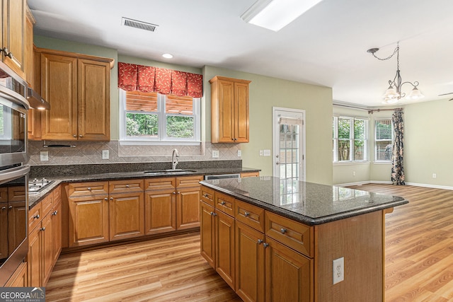 kitchen featuring light wood-style floors, a sink, brown cabinets, and visible vents