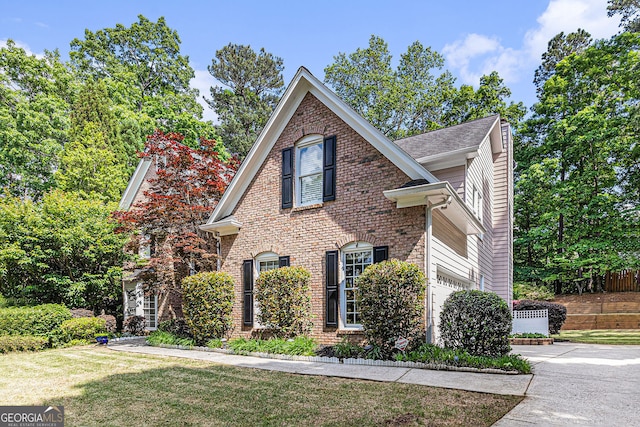 traditional-style house featuring concrete driveway, brick siding, an attached garage, and a front yard