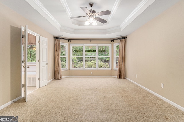 empty room featuring ornamental molding, light carpet, a tray ceiling, and ceiling fan