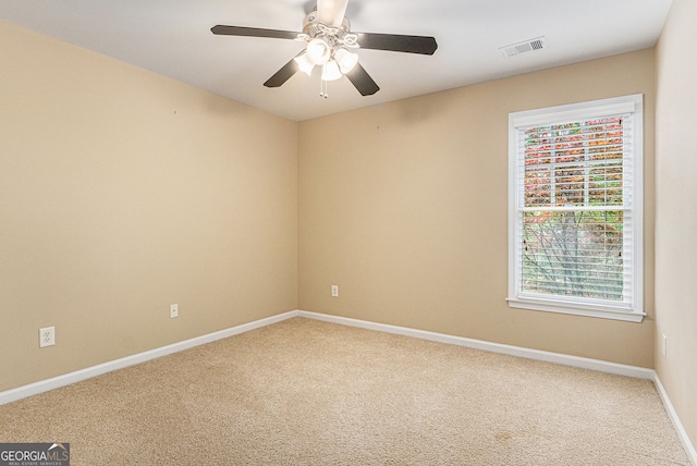 spare room featuring carpet floors, baseboards, a ceiling fan, and visible vents