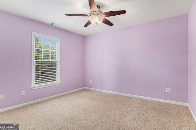 spare room with a ceiling fan, light colored carpet, visible vents, and baseboards