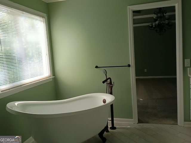 full bath with baseboards, a freestanding tub, a healthy amount of sunlight, and wood finished floors