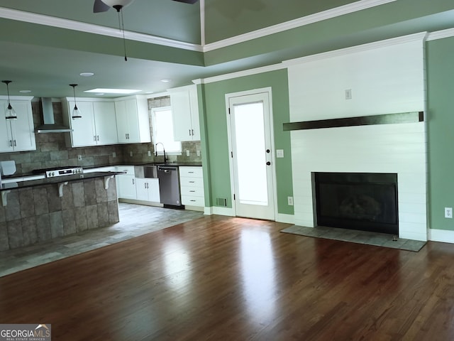 kitchen featuring stainless steel dishwasher, open floor plan, wall chimney exhaust hood, and dark countertops