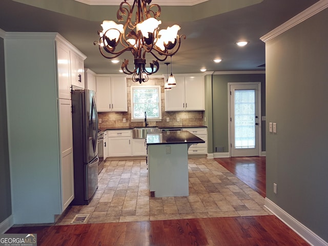 kitchen with crown molding, freestanding refrigerator, and visible vents