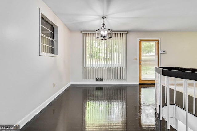 unfurnished dining area featuring baseboards and a notable chandelier