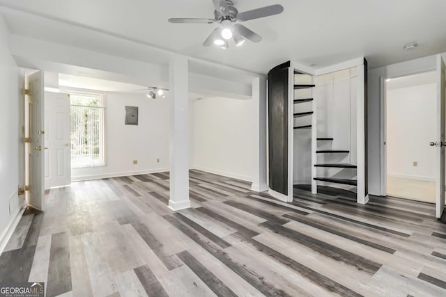 below grade area featuring stairs, baseboards, wood finished floors, and electric panel