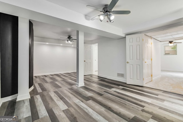 below grade area with a ceiling fan, visible vents, and wood finished floors
