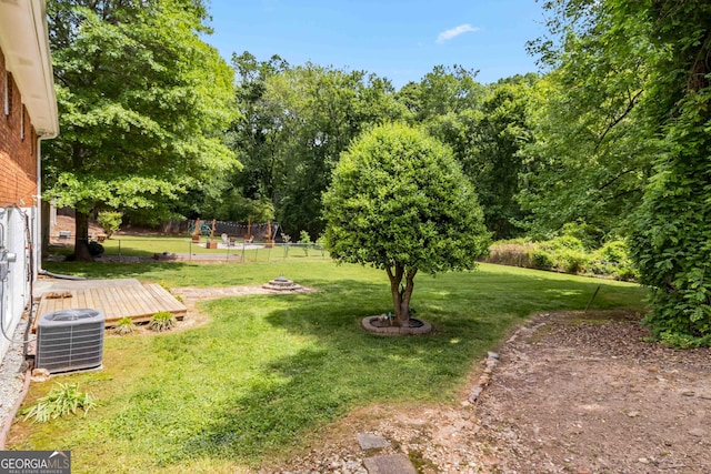 view of yard featuring fence, a wooden deck, and central AC