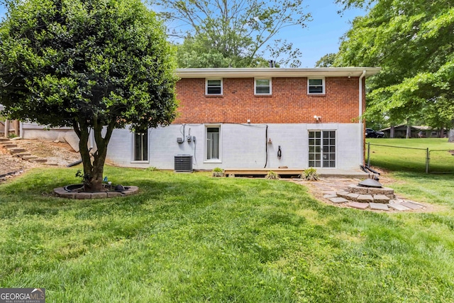 back of house featuring a lawn, brick siding, cooling unit, and fence
