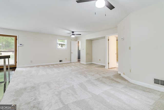 unfurnished room with baseboards, ceiling fan, light colored carpet, and visible vents