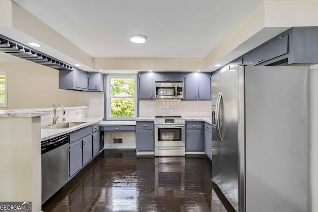 kitchen featuring decorative backsplash, dark wood-style floors, a sink, gray cabinetry, and stainless steel appliances