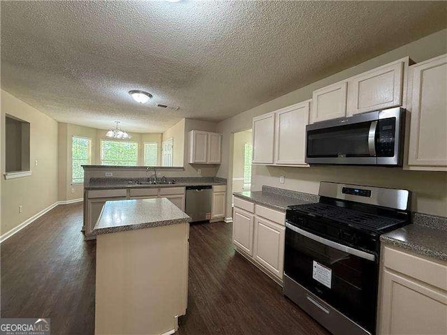 99 Ashtonbrook Dr, Mcdonough, GA 30252 - kitchen with a peninsula, a textured ceiling, white cabinetry, dark wood finished floors, and stainless steel appliances