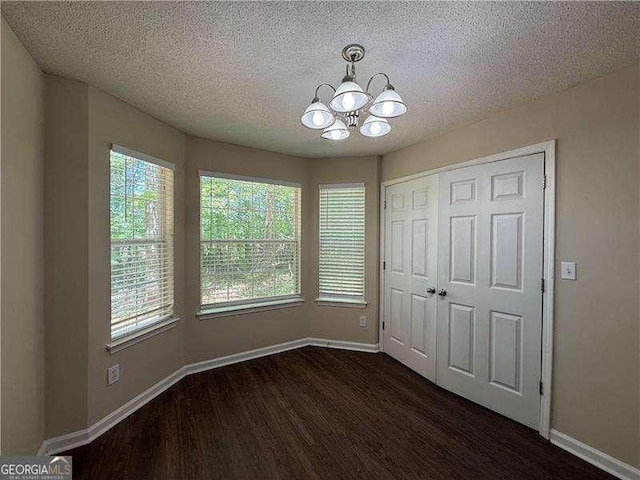 99 Ashtonbrook Dr, Mcdonough, GA 30252 - unfurnished dining area featuring baseboards, a textured ceiling, dark wood-style flooring, and a chandelier