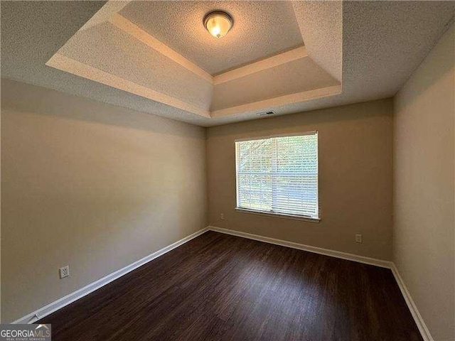 99 Ashtonbrook Dr, Mcdonough, GA 30252 - empty room featuring dark wood-style flooring, a textured ceiling, visible vents, baseboards, and a tray ceiling