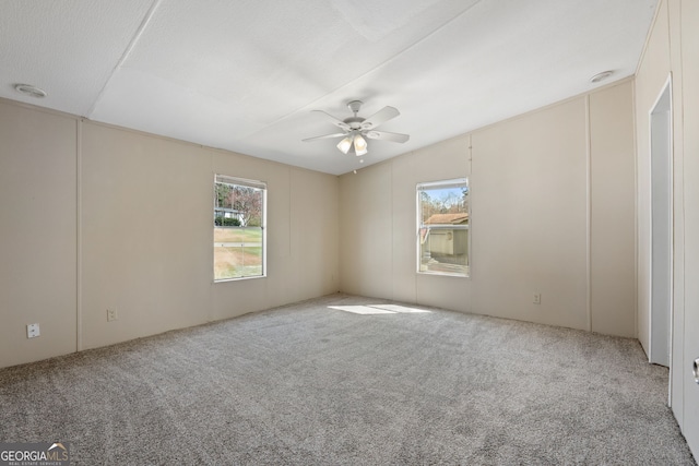 carpeted spare room with a healthy amount of sunlight and a ceiling fan