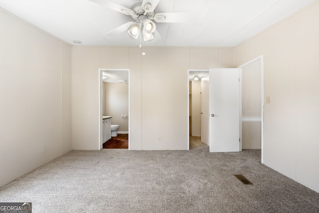 unfurnished bedroom featuring ensuite bathroom, carpet, and visible vents