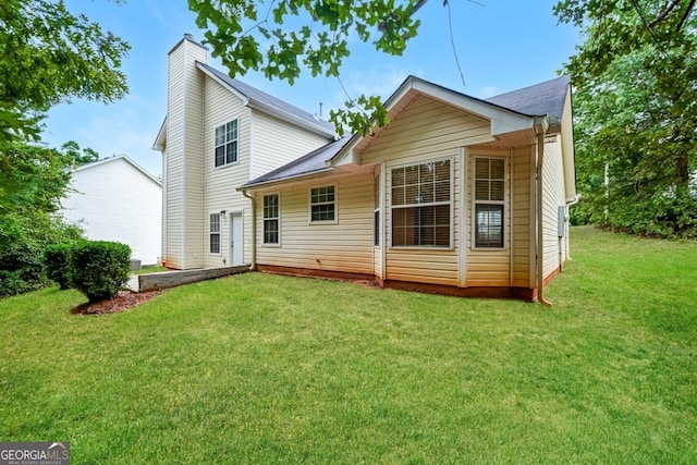 back of property with a chimney and a yard