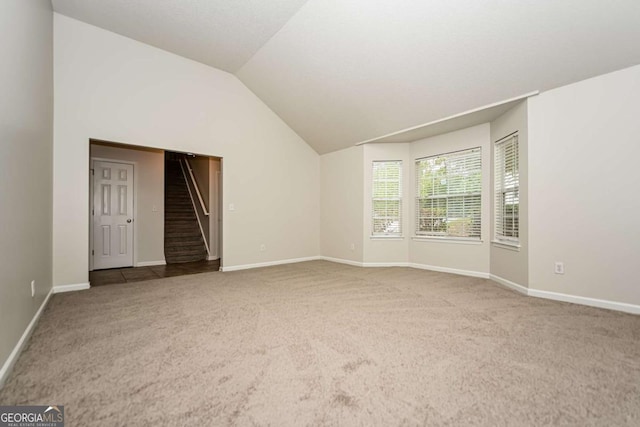 unfurnished living room with carpet flooring, baseboards, vaulted ceiling, and stairs