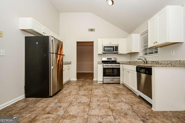 kitchen with visible vents, white cabinets, vaulted ceiling, and stainless steel appliances