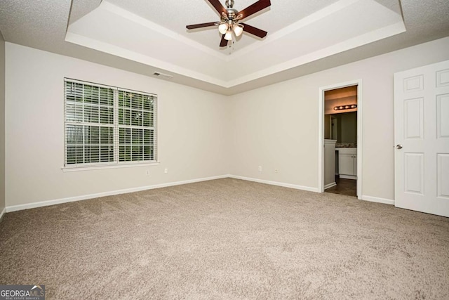 unfurnished bedroom with visible vents, carpet, and a raised ceiling