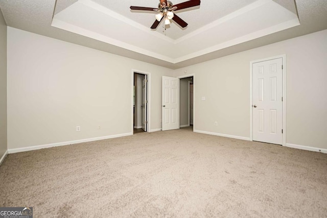 unfurnished bedroom with baseboards, a tray ceiling, and carpet flooring
