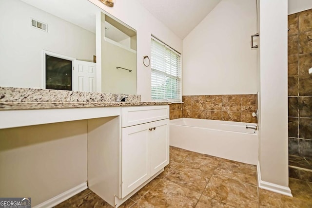 bathroom with vanity, lofted ceiling, a bath, and visible vents