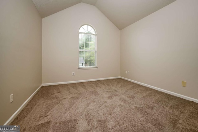 carpeted spare room with baseboards and lofted ceiling