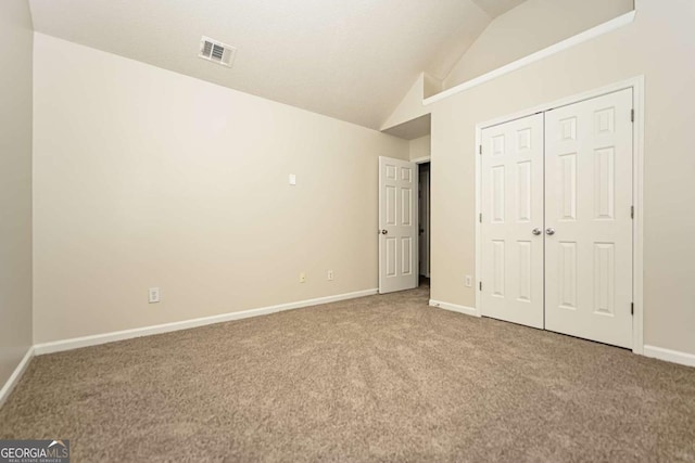 unfurnished bedroom featuring visible vents, vaulted ceiling, baseboards, a closet, and carpet flooring