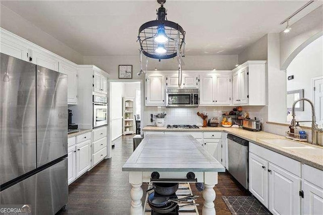 kitchen featuring decorative backsplash, a sink, light countertops, stainless steel appliances, and white cabinetry