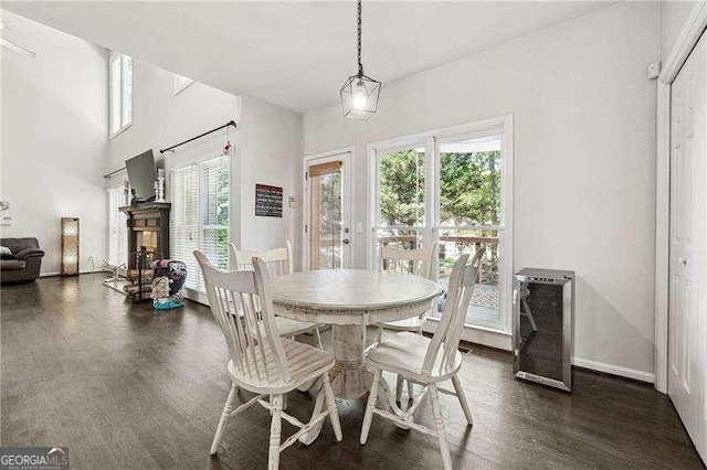 dining space featuring french doors, a fireplace, baseboards, wine cooler, and dark wood-type flooring
