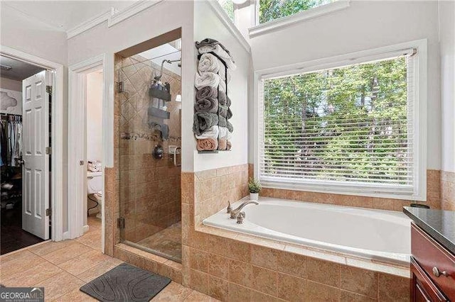 bathroom featuring tile patterned flooring, a stall shower, toilet, and a garden tub