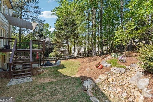 view of yard with fence, a wooden deck, and stairway