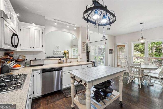 kitchen with dark wood-style flooring, light countertops, white cabinetry, rail lighting, and appliances with stainless steel finishes