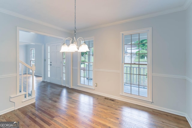 unfurnished dining area featuring an inviting chandelier, crown molding, wood finished floors, and visible vents