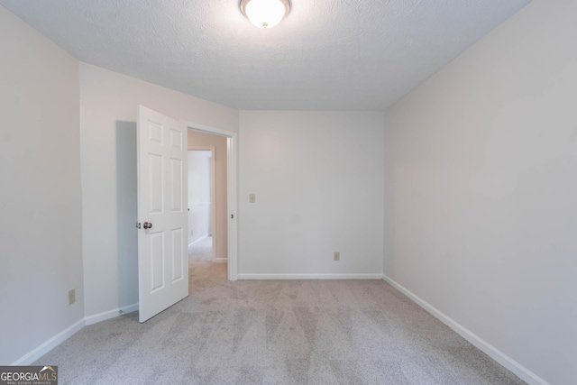 spare room featuring baseboards, carpet flooring, and a textured ceiling