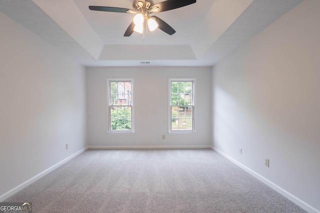 spare room with baseboards, carpet, a tray ceiling, and visible vents