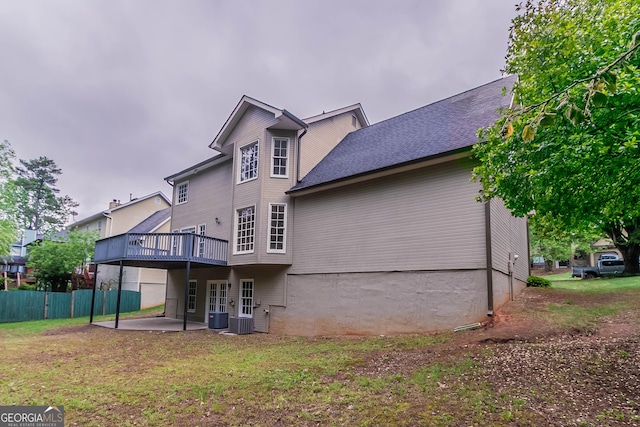 rear view of house with a lawn, a wooden deck, a patio area, central air condition unit, and fence