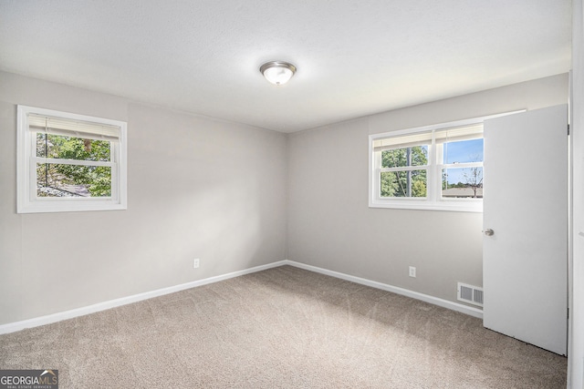carpeted empty room featuring visible vents and baseboards