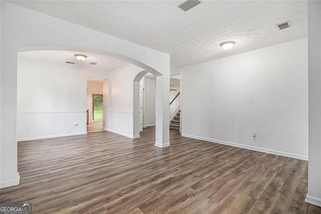 7454 Silver Arrow Trl SE, Austell, GA 30168 - spare room with dark wood-style floors, arched walkways, stairs, and a textured ceiling