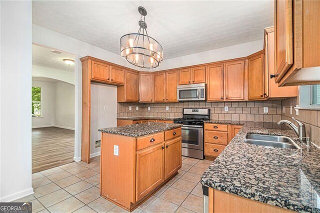 7454 Silver Arrow Trl SE, Austell, GA 30168 - kitchen featuring stainless steel appliances, dark stone counters, a kitchen island, tasteful backsplash, and arched walkways