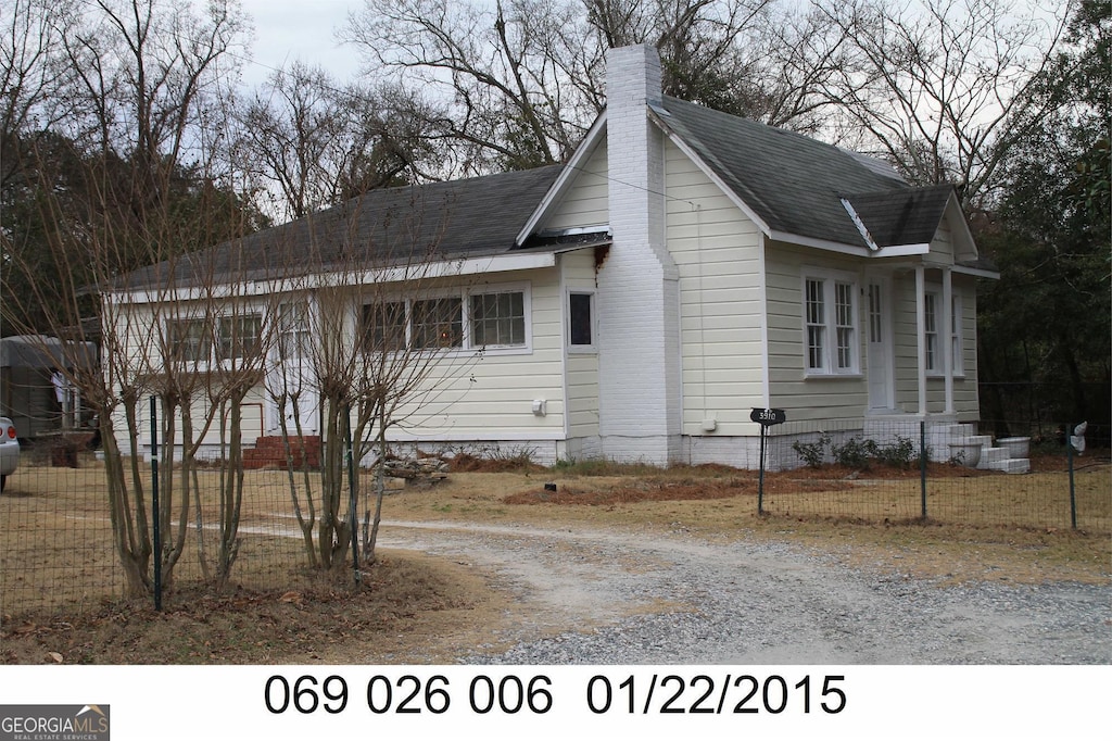 view of side of home with fence, a chimney, and a shingled roof