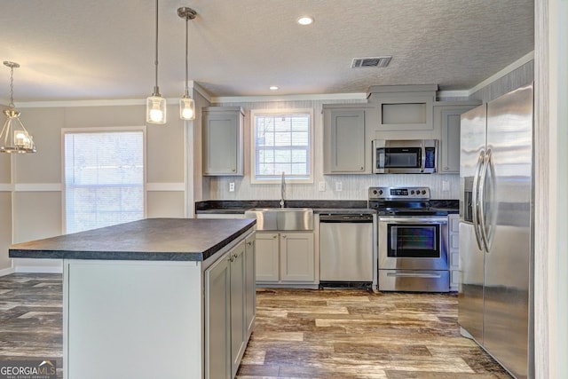 kitchen with visible vents, wood finished floors, dark countertops, a sink, and stainless steel appliances